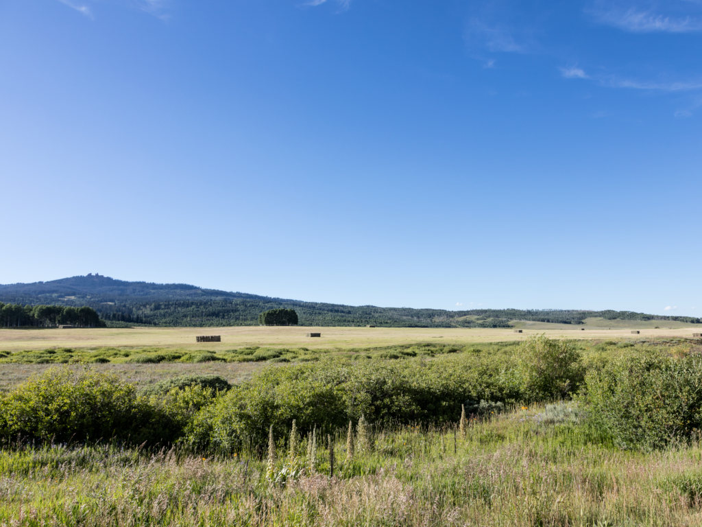side view of Rabbit Ears Pass from a meadow with hay bales showing the mountain pass