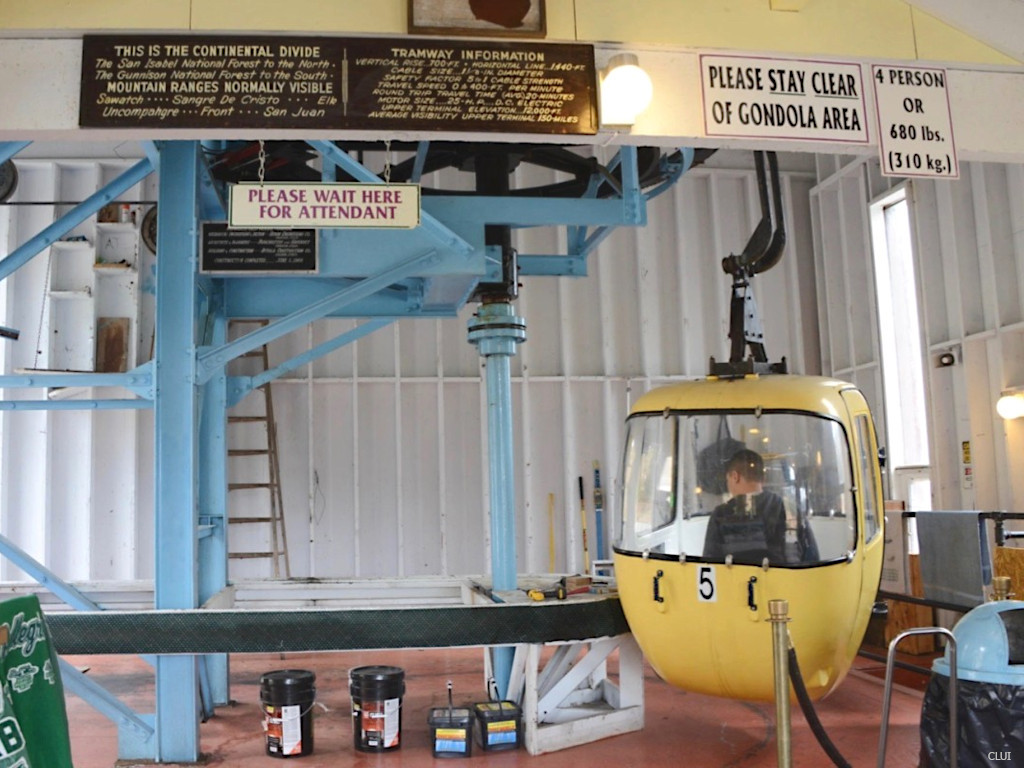 Inside Monarch Pass tramway station at bottom with gondola cabins and signs